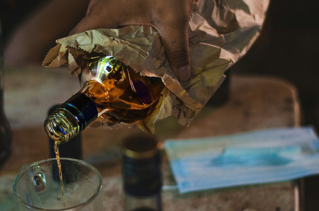 Garrafa de álcool sendo colocada em copo