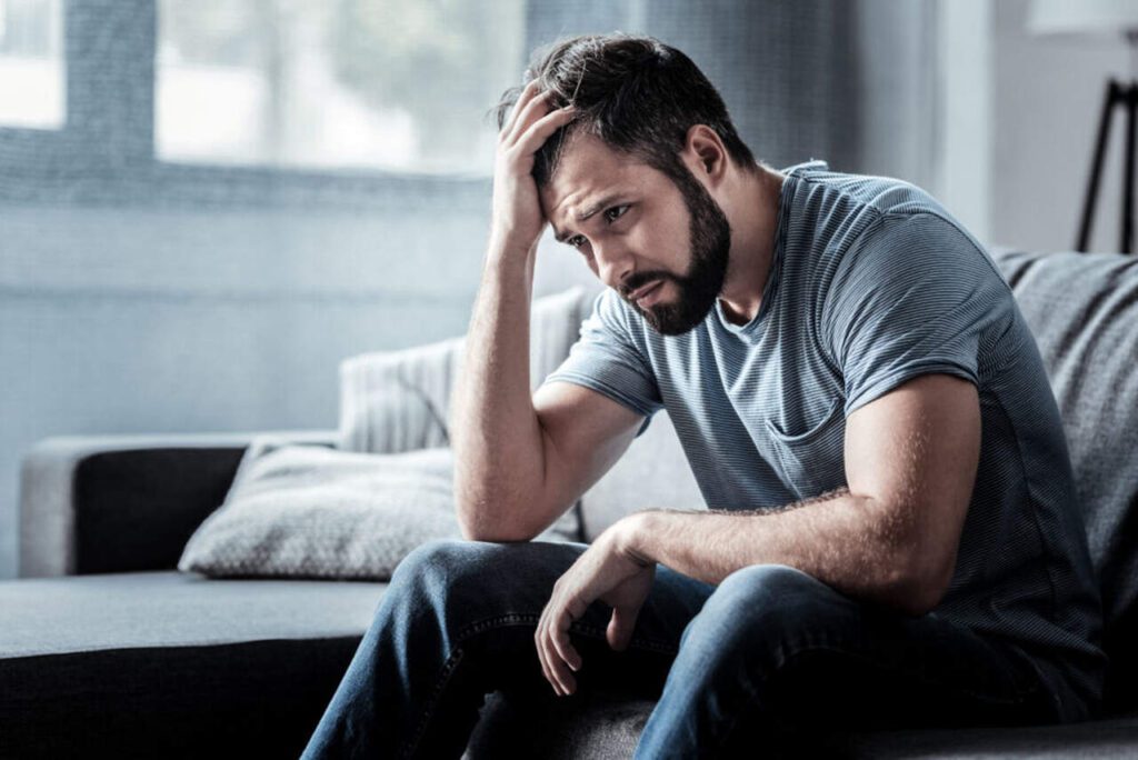 Homem com mão na cabeça e sintomas de depressão masculina
