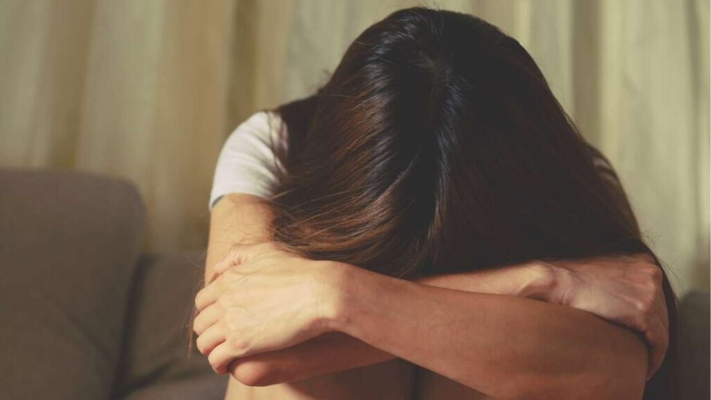 Mulher sentada sofrendo de cabe&ccedil;a baixa