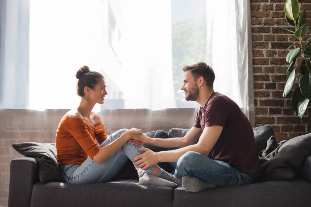 Homem e mulher sentados em sofá conversando