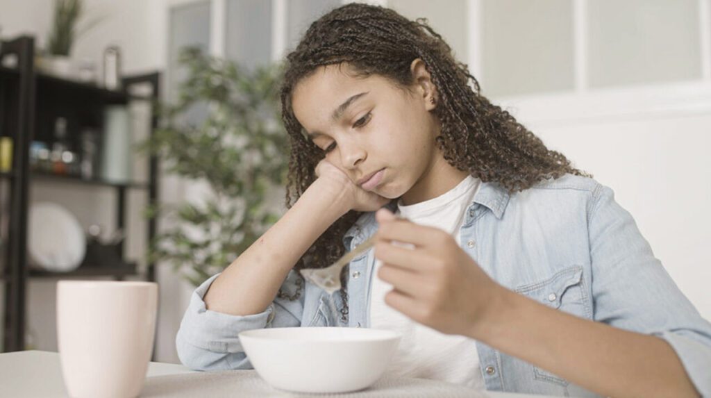 Menina triste olhando para comida
