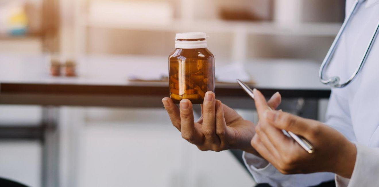 Profissional de saúde segurando um frasco de medicamento durante uma consulta